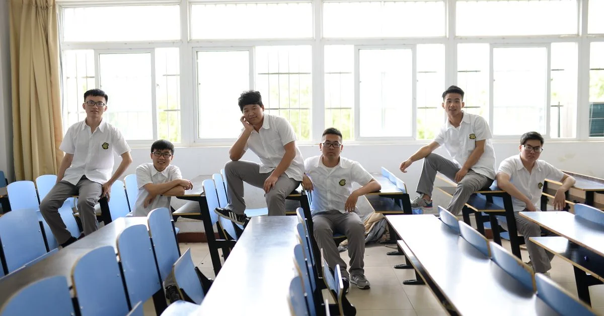 De jeunes étudiants en uniforme assis dans une salle de classe lumineuse, posant avec désinvolture.