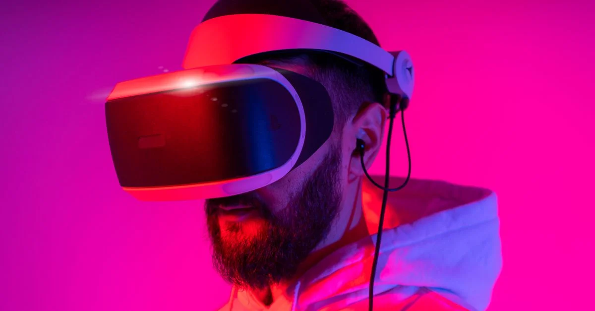 Un homme portant un casque VR est immergé dans la réalité virtuelle, illuminé par un éclairage rose vibrant.