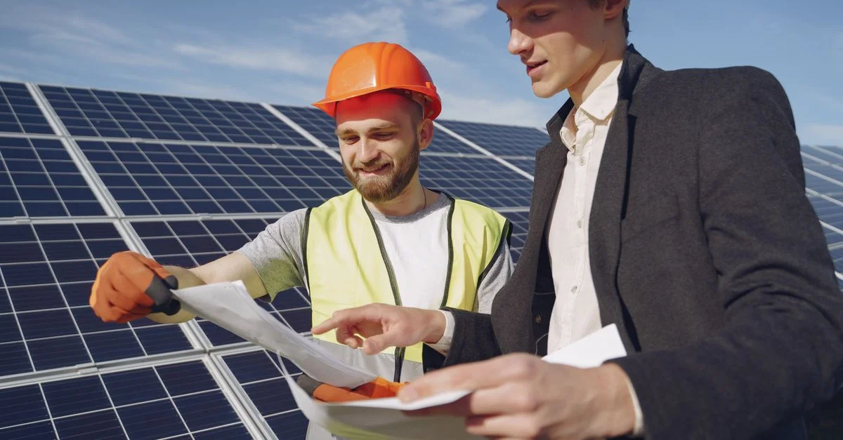 Deux ingénieurs examinent des plans pour l'installation de panneaux solaires, représentant le travail d'équipe dans les énergies renouvelables.