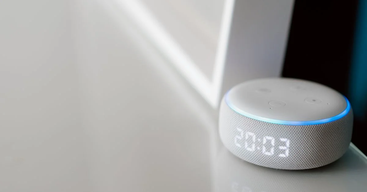 Gros plan d'une enceinte intelligente avec affichage numérique sur une surface minimaliste.