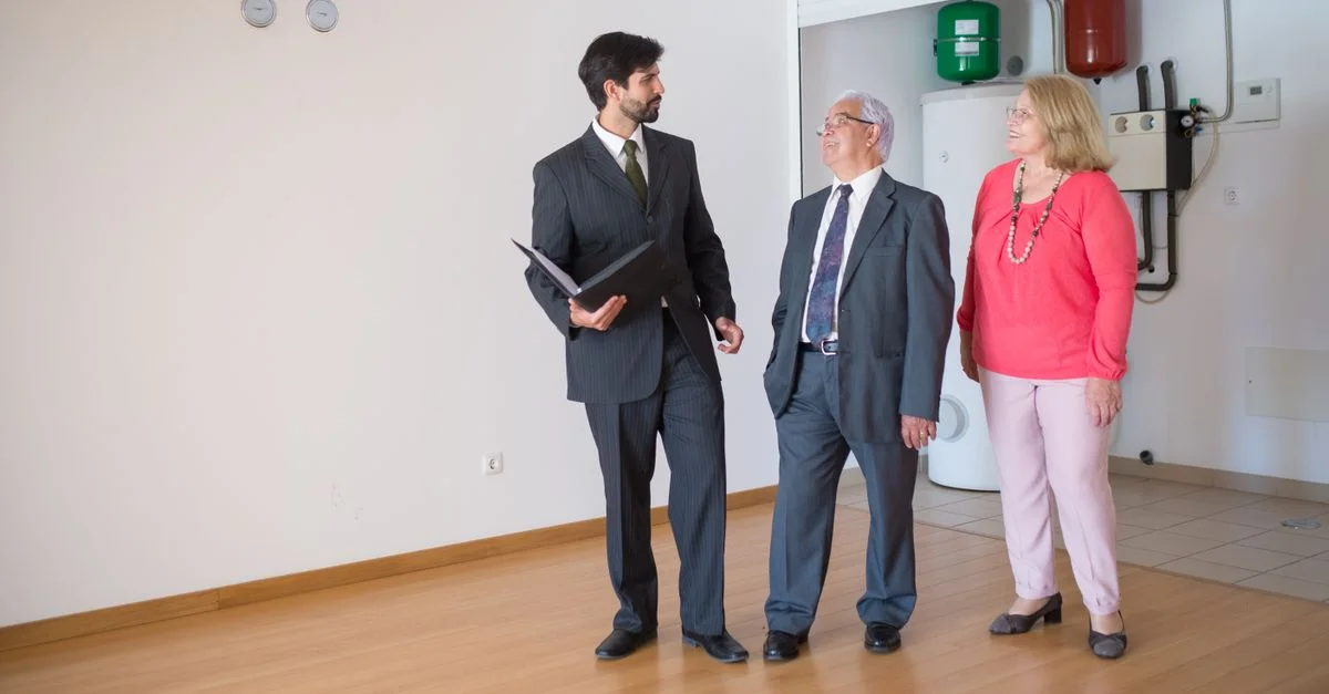 Un couple âgé visitant une maison avec un agent immobilier, discutant des options immobilières.
