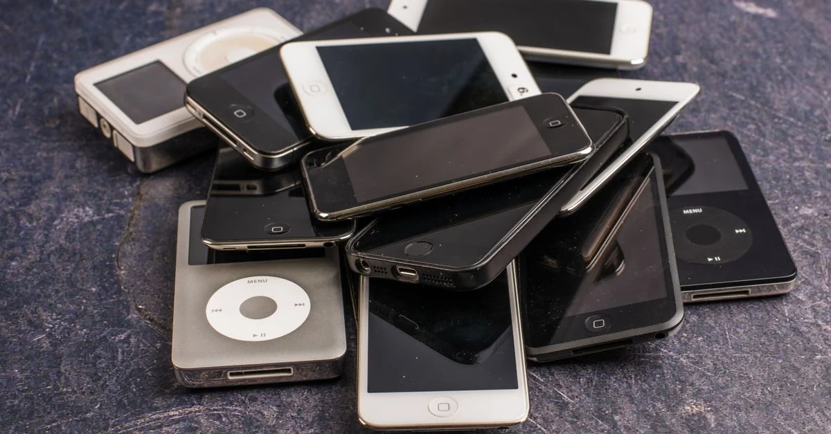 Une collection de vieux lecteurs MP3 et smartphones empilés sur une table.