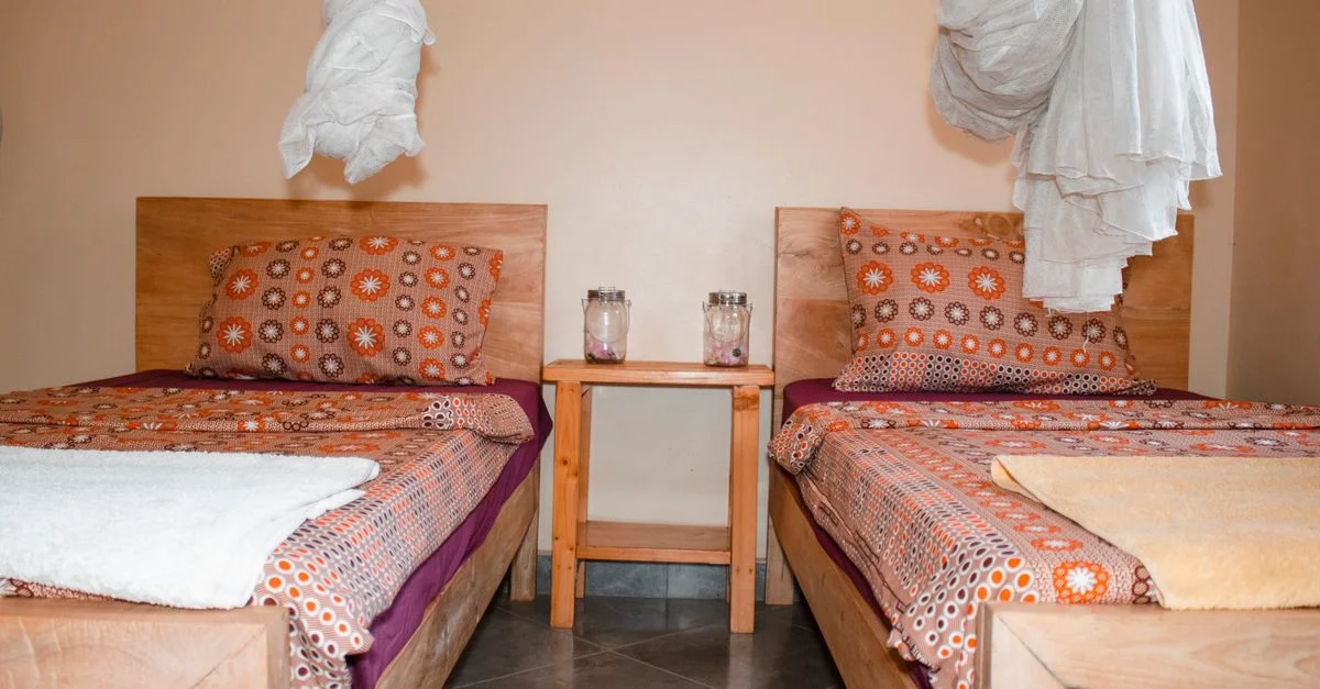 Chambre double confortable avec moustiquaires et literie colorée à Kampala, en Ouganda.
